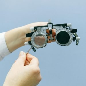 Hands adjusting an optometry trial lens set with a blue background. Ideal for vision and health topics.